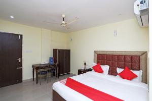 a bedroom with a bed with red pillows and a desk at OYO Ma Classic Inn in Bhubaneshwar