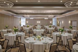 una sala de banquetes con mesas y sillas blancas y lámparas de araña en Delta Hotels by Marriott Chicago Willowbrook, en Willowbrook