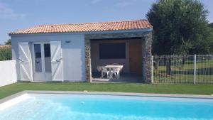un pequeño cobertizo con una mesa y una piscina en Les bougainvilliers, en Penta-di-Casinca