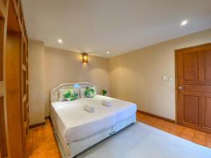 a bedroom with a white bed and a wooden door at Villano Lilawadee Pool Villa in Na Jomtien