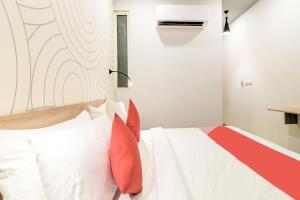 una camera da letto con un letto bianco con cuscini rossi di Collection O Jps Grand Hotel Near Dwarka Metro Station a Nuova Delhi