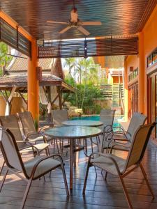 a patio with chairs and tables and a ceiling fan at Villano Lilawadee Pool Villa in Na Jomtien