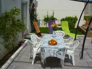 una mesa blanca con sillas blancas y un bol de fruta en Les bougainvilliers, en Penta-di-Casinca