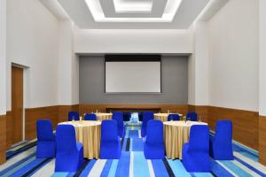 une salle de conférence avec des tables, des chaises et un écran dans l'établissement Fairfield by Marriott Hyderabad Gachibowli, à Hyderabad