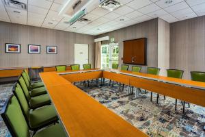 una sala de conferencias con una mesa larga y sillas verdes en SpringHill Suites Vero Beach, en Vero Beach