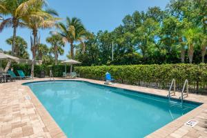 a swimming pool with a fence and palm trees at SpringHill Suites Vero Beach in Vero Beach