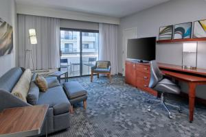 a living room with a couch and a desk in a hotel room at Courtyard by Marriott Indianapolis Castleton in Indianapolis