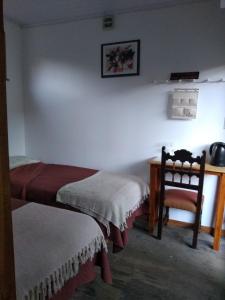 Cette chambre comprend deux lits, un bureau et une chaise. dans l'établissement Aguaymanto, à Cuchilla Alta