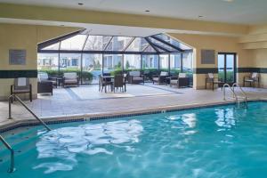 una piscina en un hotel con mesas y sillas en Courtyard by Marriott Indianapolis Castleton, en Indianápolis