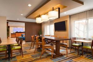 Fairfield Inn & Suites Minneapolis Bloomington/Mall of America في بلومنغتون: غرفة طعام مع طاولة وكراسي وتلفزيون
