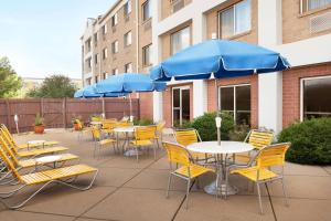 eine Terrasse mit Tischen, Stühlen und blauen Sonnenschirmen in der Unterkunft Fairfield Inn & Suites Minneapolis Bloomington/Mall of America in Bloomington