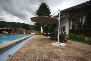 un patio con sombrilla junto a una piscina en Chalet con piscina en Peón "Los Tres Robles", 