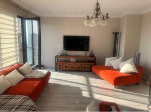 - un salon avec deux canapés orange et une télévision à écran plat dans l'établissement Dlk İmmobilien, à Istanbul