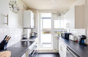 a kitchen with white cabinets and a large window at Cosy 2 bed apartment close to CC - Free parking in Manchester