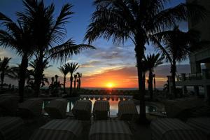a sunset at a resort with chairs and palm trees at Sandpearl Resort Private Beach in Clearwater Beach