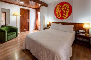 a bedroom with a large bed and a green chair at Hotel A.S. Sao Joao da Madeira in São João da Madeira