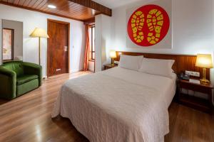 - une chambre avec un grand lit et une chaise verte dans l'établissement Hotel A.S. Sao Joao da Madeira, à São João da Madeira