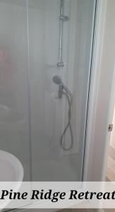 a shower in a bathroom with a wire ridge renewal sign at Pine Ridge Retreat With FREE GOLF and Air Conditioning in Morpeth