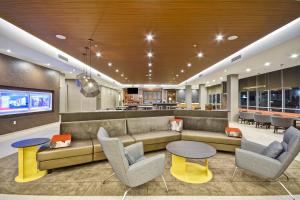 a lobby with a couch and chairs and a bar at SpringHill Suites by Marriott Cincinnati Blue Ash in Blue Ash