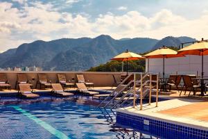 a swimming pool with chairs and tables and umbrellas at Residence Inn by Marriott Rio de Janeiro Barra da Tijuca in Rio de Janeiro