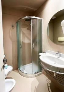 uma casa de banho com uma cabina de duche em vidro e um lavatório. em Hotel Little em Rimini