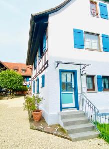 a white house with a blue door and stairs at Barbarahof in Markdorf