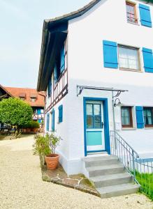 ein weißes Haus mit blauer Tür und Treppe in der Unterkunft Barbarahof Ferienwohnung Vita Erdgeschoss in Markdorf