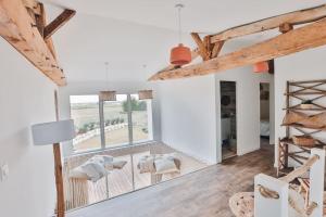 una sala de estar con paredes blancas y vigas de madera. en Le Clos De L'olivier, en Grézac