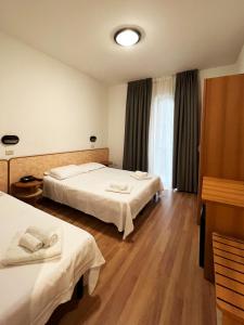 una camera d'albergo con due letti e una finestra di Hotel Little a Rimini