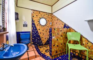 a bathroom with a blue sink and a green chair at Cabinas Jacaranda in Puerto Viejo