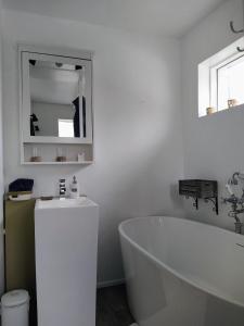 a white bathroom with a tub and a sink at Flateyri guesthouse in Flateyri