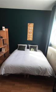 - une chambre avec un grand lit et un mur vert dans l'établissement La cachette de Chartres, à Chartres