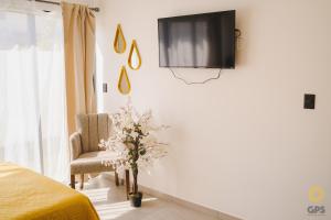a bedroom with a tv on the wall and a chair at Hotel boutique 402 in Mazatlán