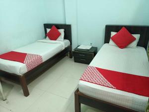 Duas camas com almofadas vermelhas num quarto em Flagship Om Gulmohar Avenue em Bhopal