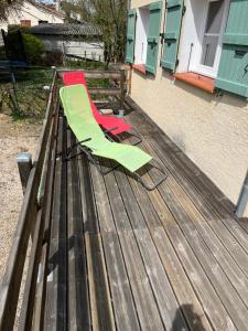 2 chaises vertes et rouges assises sur une terrasse en bois dans l'établissement Logement, à Vic-Fezensac