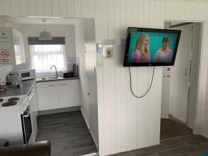 a flat screen tv hanging on a wall in a kitchen at bulldog holidays 244 in Hemsby