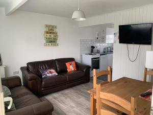 a living room with a brown couch and a kitchen at bulldog holidays 244 in Hemsby