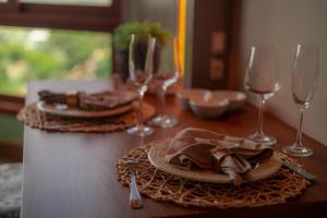 a wooden table with two plates and wine glasses at Blue Flat Pedra Azul - Com Vista pra Pedra in Pedra Azul