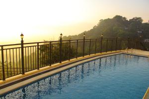 a swimming pool with a fence and mountains in the background at Hotel Sky Gate kandy in Kandy