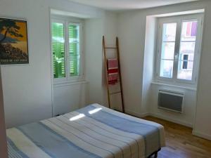 a bedroom with a bed and two windows at Charmant T3 Centre ville Corté in Corte