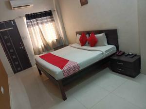 um pequeno quarto com uma cama com almofadas vermelhas em Flagship Om Gulmohar Avenue em Bhopal