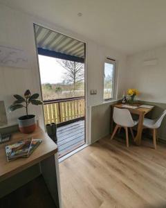 a room with a desk and a table and a balcony at Cotts Cabin - Welcombe - 2 min walk to pub in Bideford