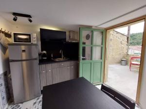 a kitchen with a green door and a refrigerator at Le Cantou de Juliette (studio) in Prugnanes