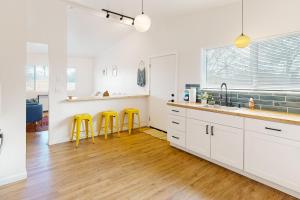 uma cozinha com armários brancos e bancos amarelos em Cherry Avenue Studio em Tucson