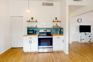 uma cozinha com armários brancos e um forno com placa de fogão em Cherry Avenue Studio em Tucson