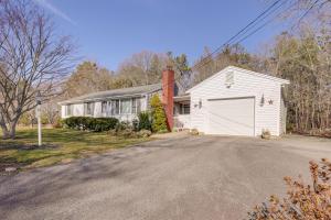 a white house with a garage on a driveway at Picturesque Barnstable Rental with Deck and Backyard! in Barnstable