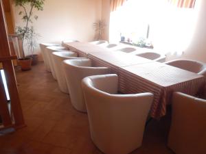 una fila de mesas y sillas blancas en una habitación en Konsky Dvor, en Brzotín