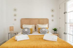 a bedroom with a large bed with a yellow blanket at Casa Nova do Levante, perto do Mar, com estacionamento privativo in Olhão