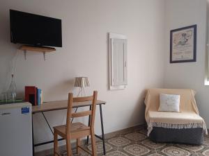 um quarto com uma secretária com uma cadeira e uma televisão em La casa di Aneupe em Siracusa