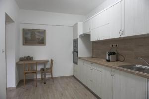 uma cozinha com armários brancos, uma mesa e um lavatório em Apartmán U Poštovských 